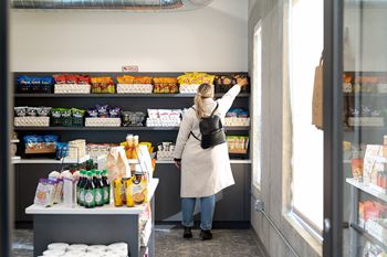 A woman in a white coat is shopping in a grocery store.